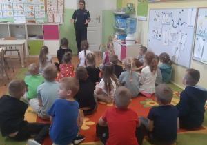 Dzieci podczas słuchania pani policjantki w czasie wizyty w przedszkolu